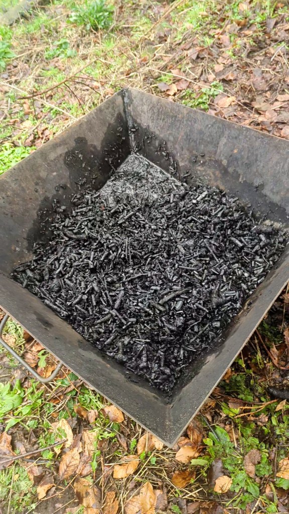 Lots of lumps of charcoal soaking in water in a steel biochar kiln.
