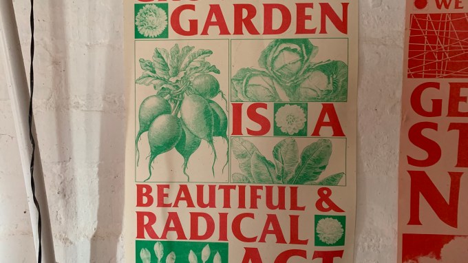 An image showing a poster hanging in the author's house, reading growing a garden is a beautiful and radical act
