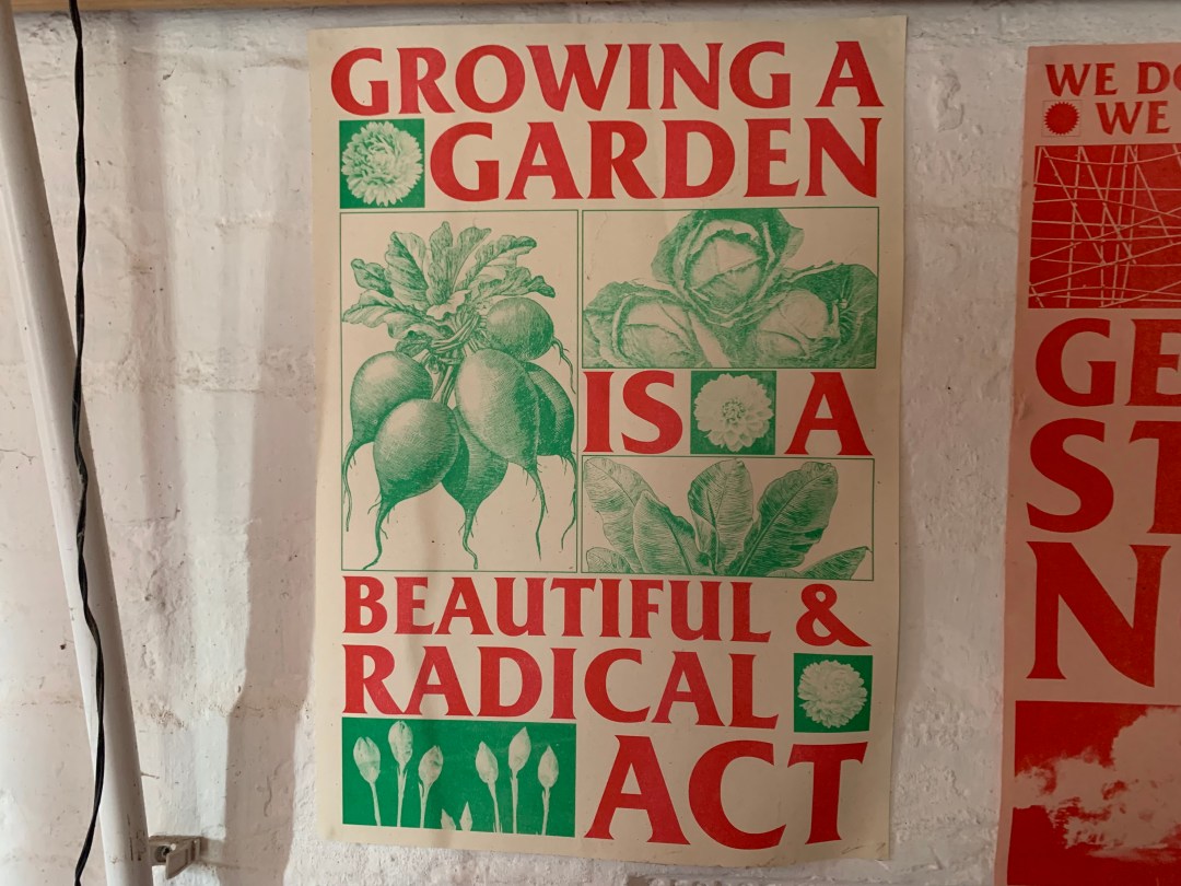 An image showing a poster hanging in the author's house, reading growing a garden is a beautiful and radical act